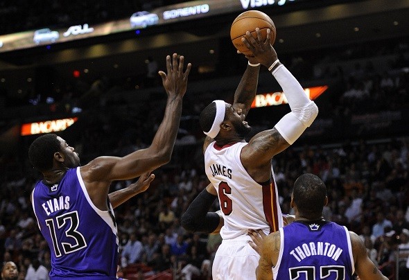 Miami Heat's LeBron James (C) is defended by Sacramento Kings' Tyreke Evans 