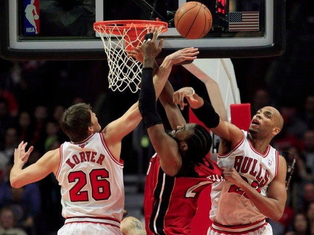 Miami Heat's Ronny Turiaf (C) is guarded by Chicago Bulls' Kyle Korver (L) and Taj Gibson