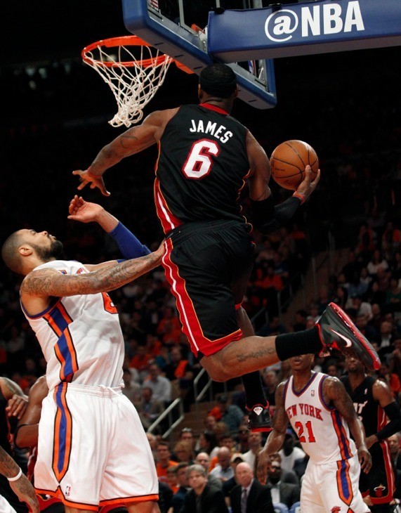 Miami Heat's Lebron James soars over New York Knicks' Tyson Chandler (L) on his way to a layup basket in the first half During their NBA basketball game in New York, April 15, 2012. 