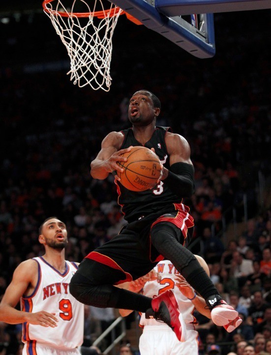 Miami Heat's Dwyane Wade soars towards the basket past New York Knicks' Jared Jeffries (L) and Landry Fields (back R) in the firs half During their NBA basketball game in New York, April 15, 2012. 