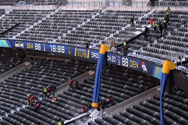 A general view as stadium workers clean snow stands during the Super Bowl XLVIII