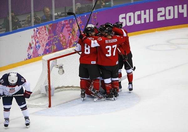 Canada celebrates their men's ice hockey semi-final win as Team USA's Phil Kessel 