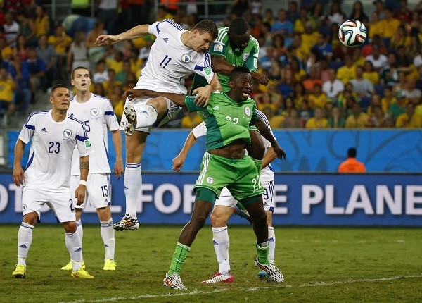Bosnia's Edin Dzeko heads the ball next to Nigeria's Kenneth Omeruo
