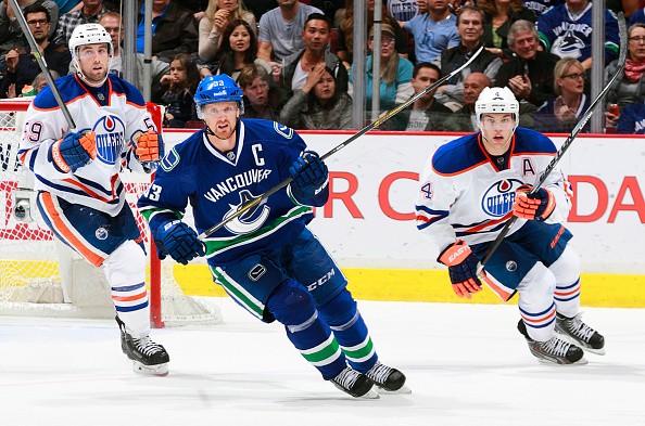 Brad Hunt #59 and Taylor Hall #4 of the Edmonton Oilers and Henrik Sedin #33 of the Vancouver Canucks 