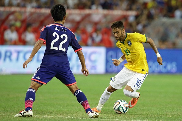 Neymar of Brazil (R) tries to dribble past Taishi Taguchi