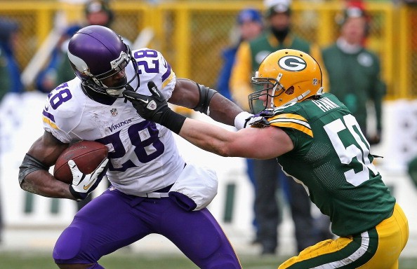 A.J. Hawk #50 of the Green Bay Packers grabs Adrian Peterson #28 of the Minnesota Vikings 