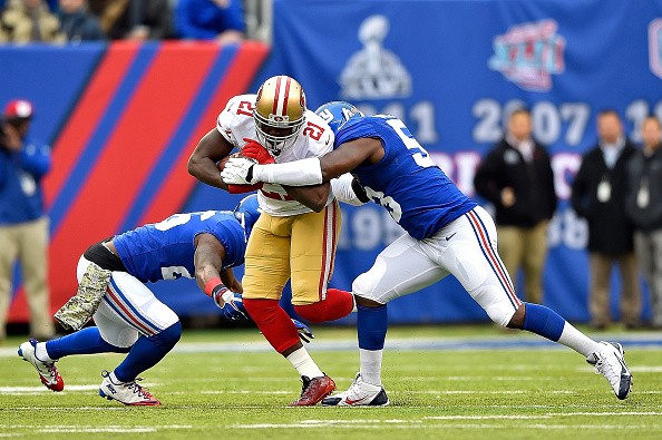 Antrel Rolle #26 and Jameel McClain #53 of the New York Giants tackle Frank Gore #21 of the San Francisco 49ers 