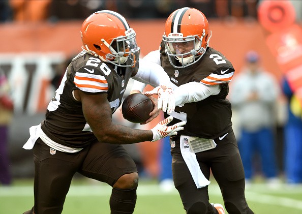 Running back Terrance West #28 of the Cleveland Browns takes the hand off from quarterback Johnny Manziel #2 