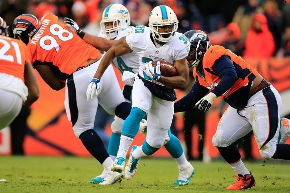Running back Daniel Thomas #30 of the Miami Dolphins rushes against the Denver Broncos