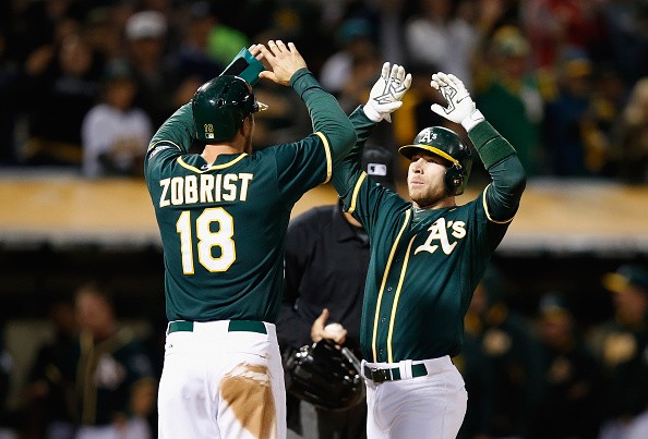 Brett Lawrie #15 of the Oakland Athletics is congratulated by Ben Zobrist #18 