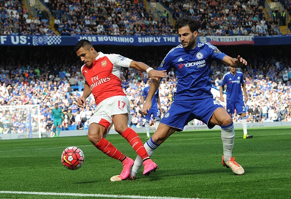 Alexis Sanchez of Arsenal is challenged by Cesc Fabregas