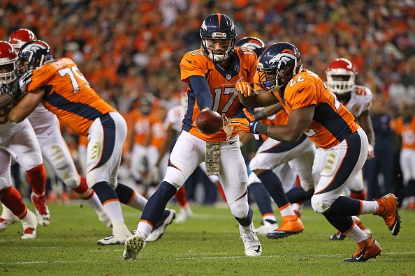 Quarterback Brock Osweiler #17 hands the ball off to C.J. Anderson #22 