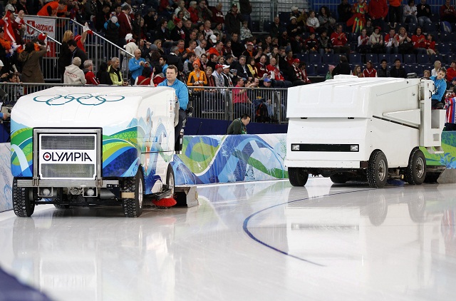 Workers using Olympia and Zamboni ice resurfacers prepare