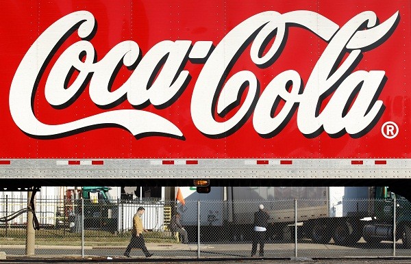 A man walks past a Coca-Cola 